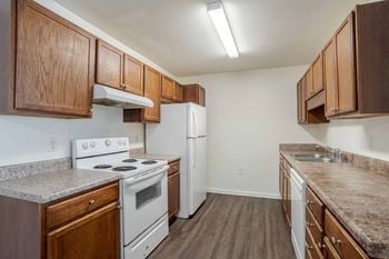 A kitchen with white appliances and wooden cabinets.